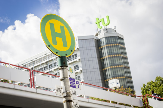 Bushaltestellenschild vor TU Dortmund Gebäude Bushaltestellenschild mit Mensabrücke und Mathetower im Hintergrund.