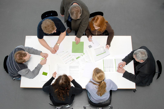 Besprechungssituation Studenten und Professoren Studierende und Dozierende sitzen gemeinsam an einem Tisch und arbeiten.